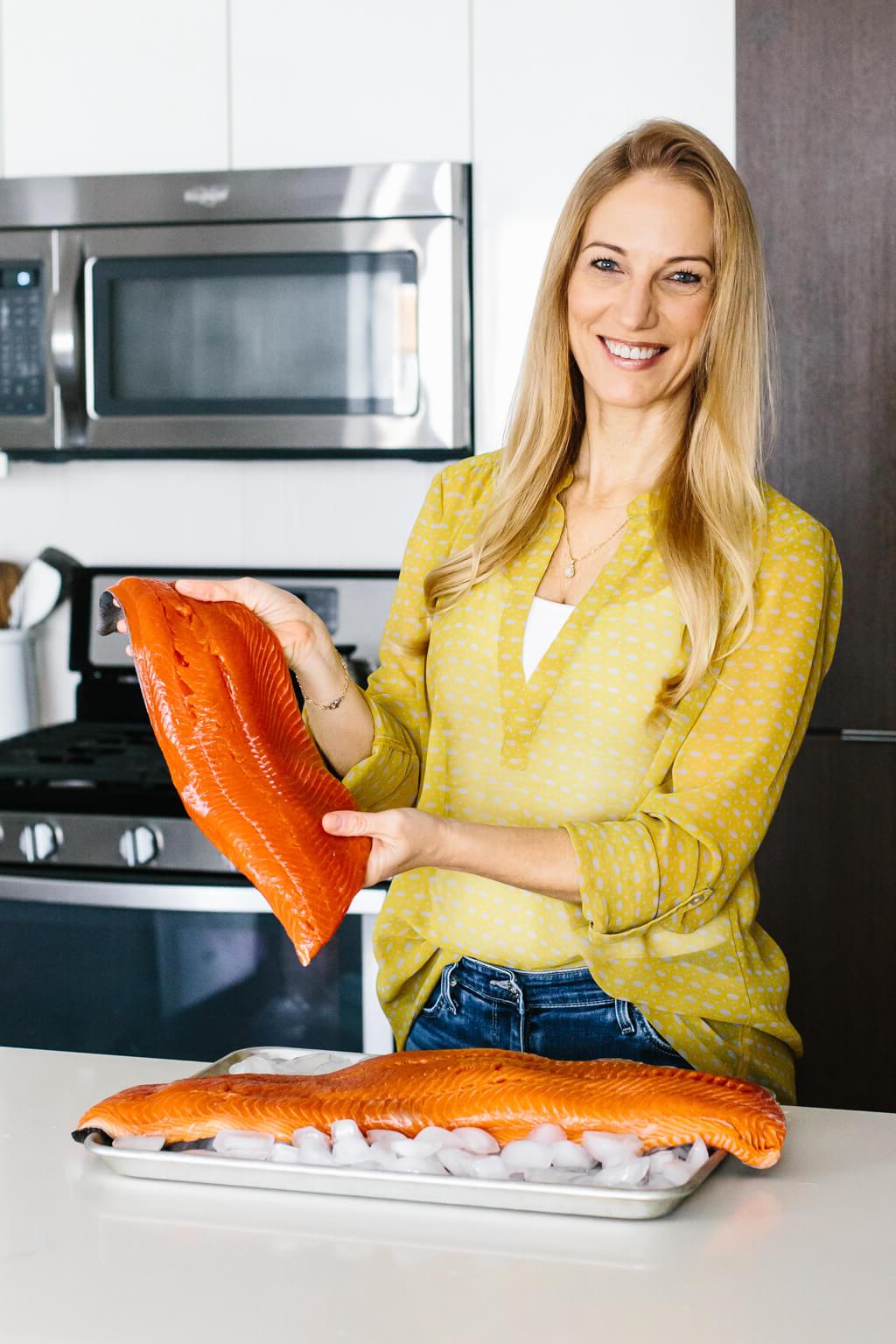 Mädchen hält ein Sockeye-Lachsfilet in einer Küche.