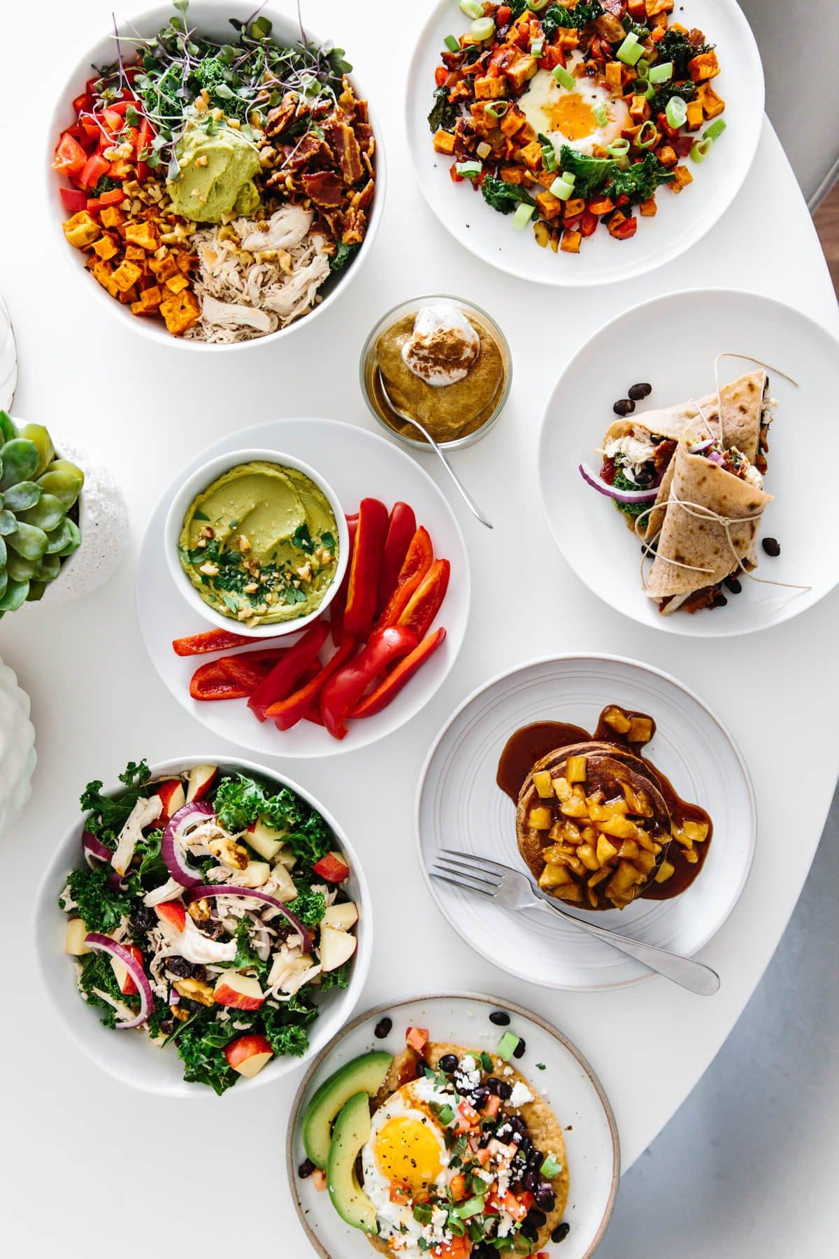 Einfache und gesunde Meal Prep Rezepte, die Ihnen helfen, Mahlzeiten für die Woche vorzubereiten! Mehrere Teller mit vorbereitetem Meal Prep Essen auf einem Tisch.