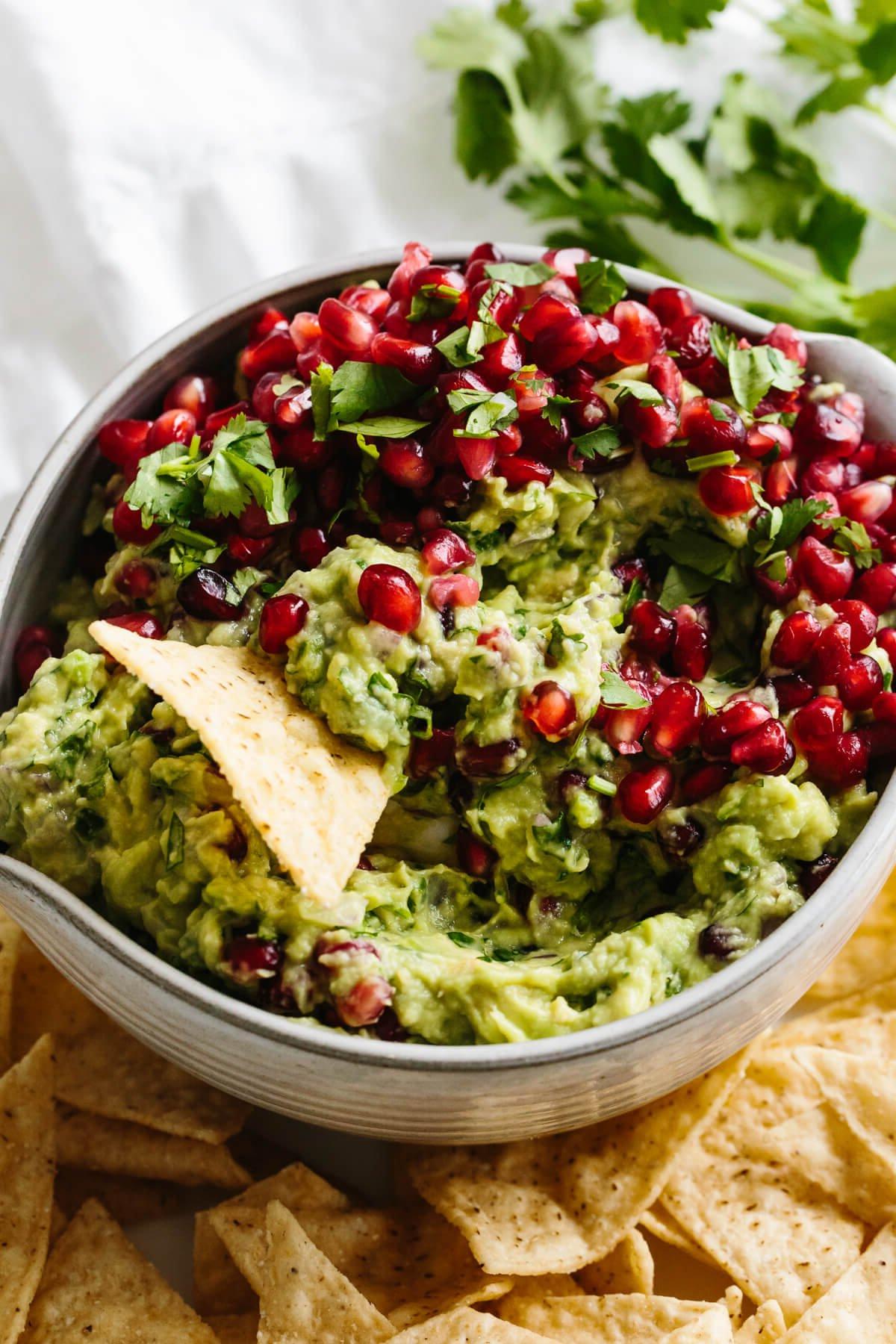 Die 10+ besten Weihnachts-Vorspeisen, die Ihre Gäste lieben werden 12 Ein Tortilla-Chip schöpft Granatapfel-Guacamole.