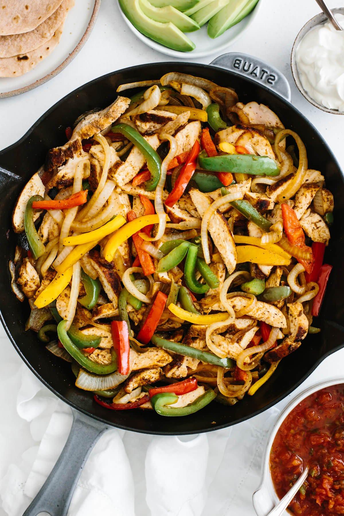 30 gesunde Rezepte in 30 Minuten oder weniger 12 Hähnchen-Fajitas in einer Pfanne auf einem Tisch mit Belägen.