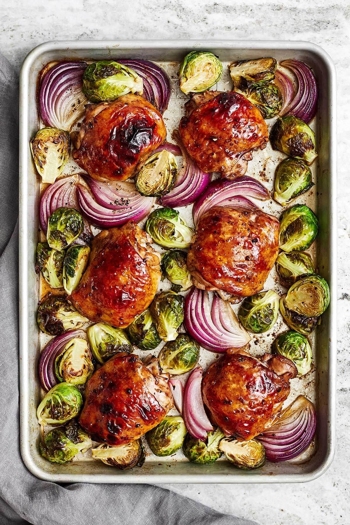 10+ Beste Hähnchenschenkel-Rezepte 13 Balsamico-Hähnchen und Rosenkohl auf einem Backblech.