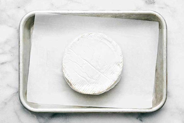 Ein Backblech mit Backpapier und Brie.
