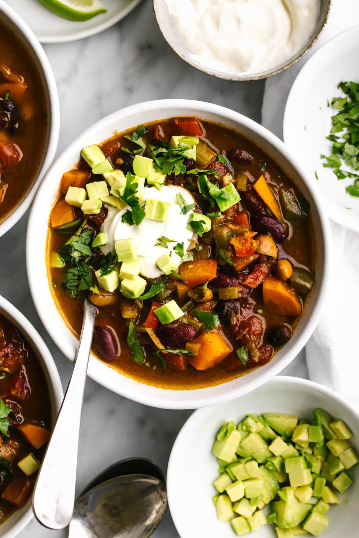 20+ Beste Suppenrezepte für Körper und Seele 16 Eine Schale vegetarisches Chili neben gewürfelter Avocado.