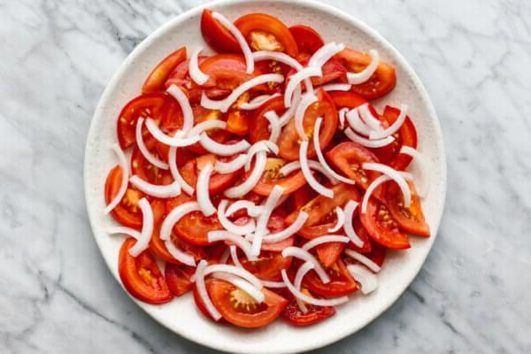 Ein Teller mit geschnittenen Tomaten und Zwiebeln für einen Avocado-Salat