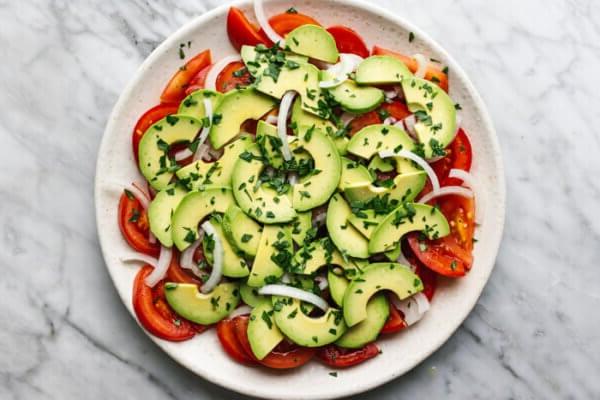 Ein Teller mit Tomaten-, Zwiebel-, Avocado-Salat