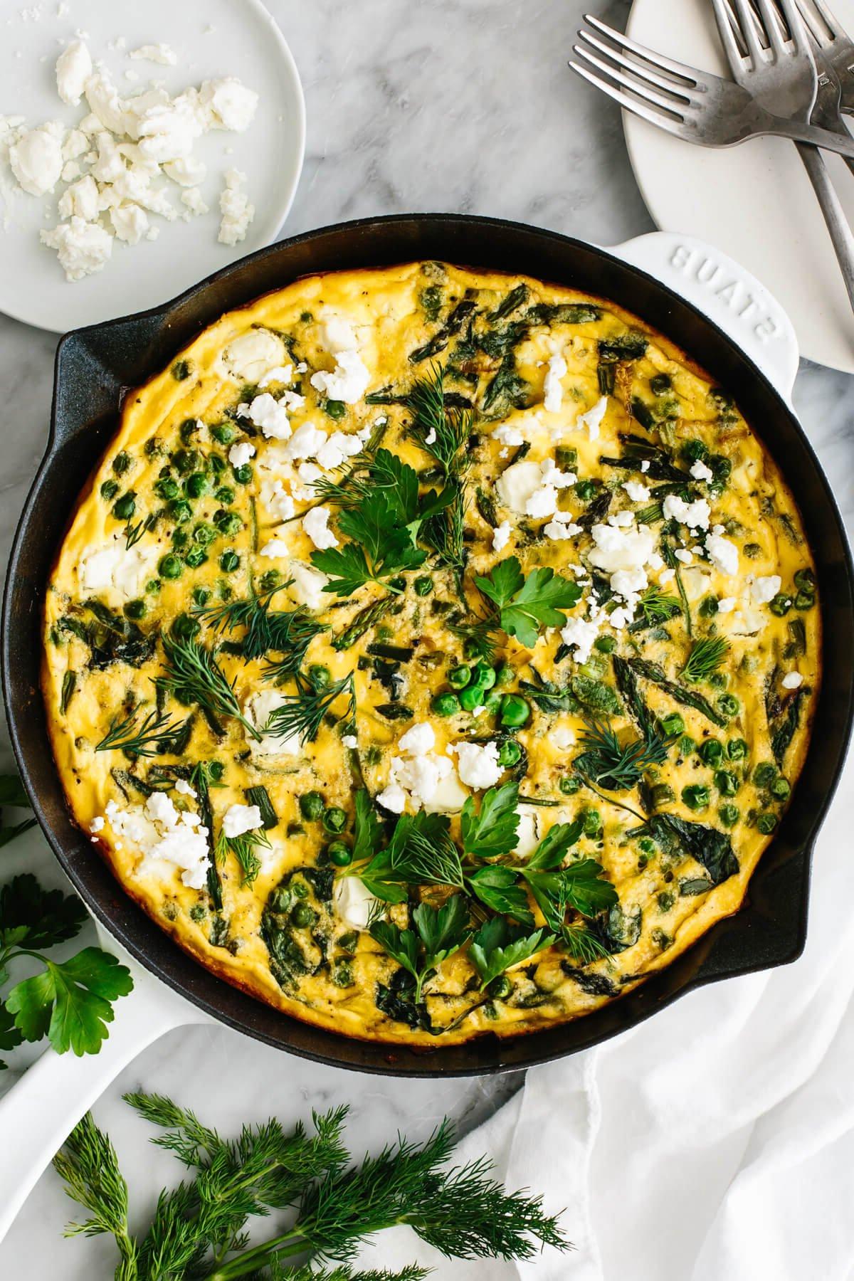 Die 60+ besten Mittelmeer-Diät-Rezepte 19 Frühlings-Gemüse-Frittata in einer Pfanne auf einem Tisch.