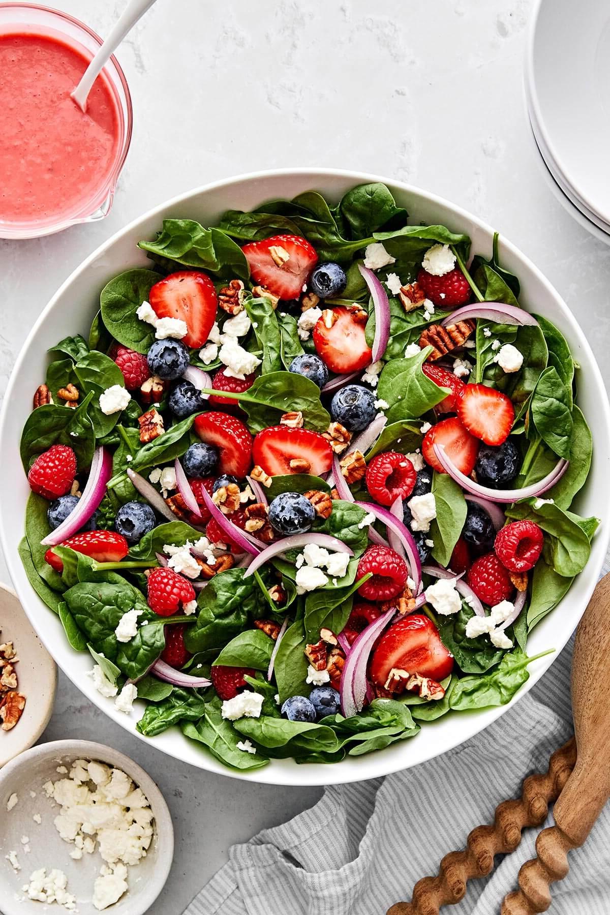 Über 30 festliche Rezepte zum 4. Juli 19 Eine Schüssel Beeren-Spinat-Salat mit Erdbeeren, Himbeeren und Blaubeeren.
