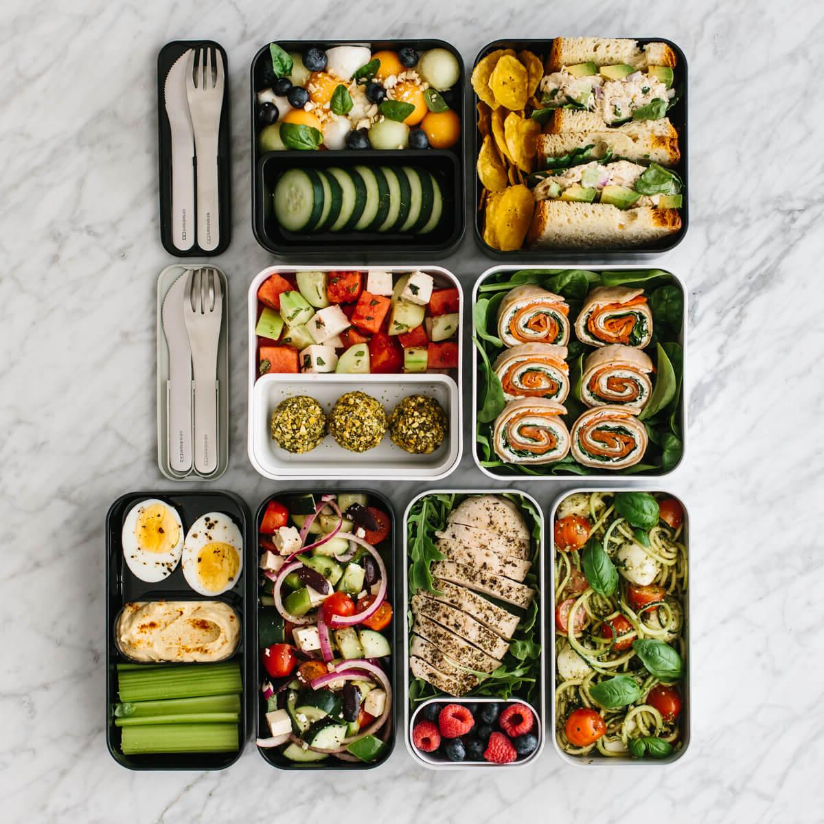Mehrere Bento-Box-Mittagessen auf einem Tresen mit Besteck.
