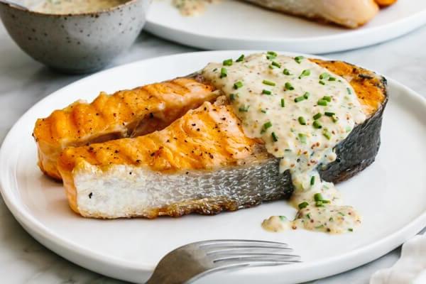 Lachssteak auf einem Teller mit Joghurtsauce beträufelt