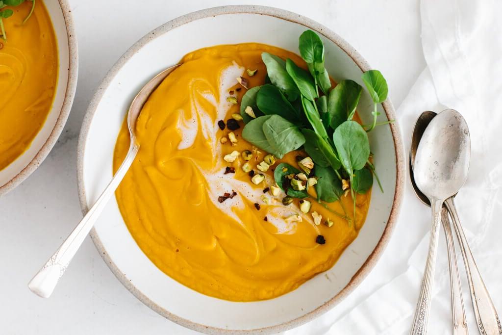 Süßkartoffelsuppe in einer weißen Schüssel mit einem Löffel.