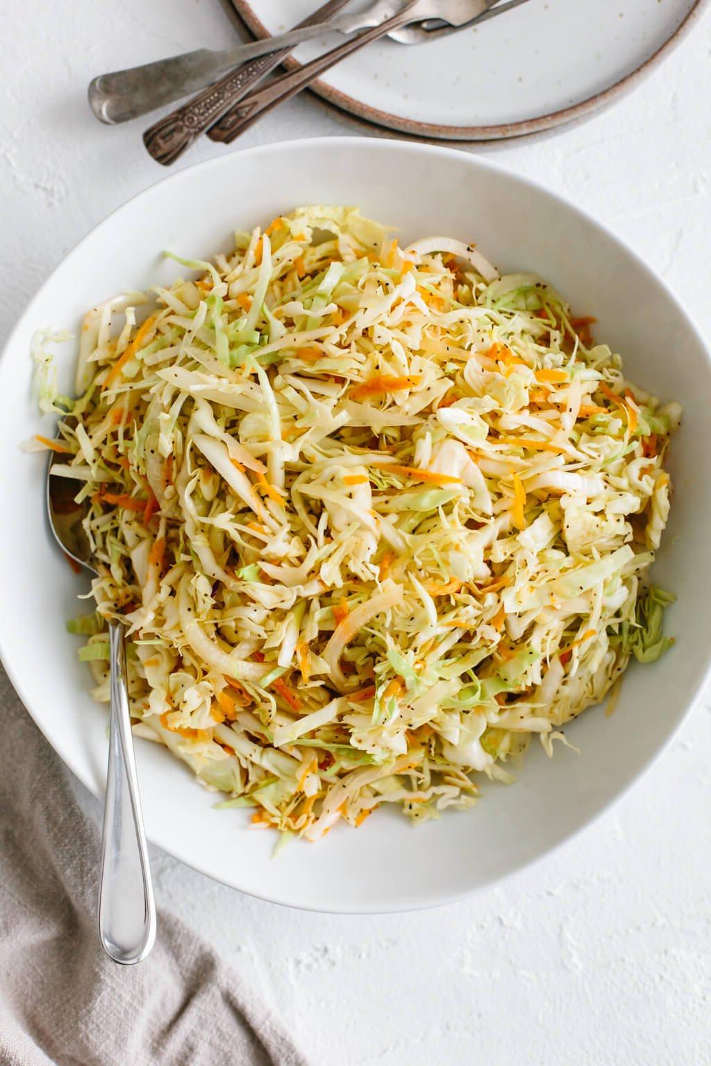 Krautsalat mit Essig-Dressing in einer weißen Schüssel angerichtet.