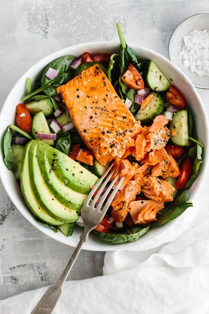 30+ Gesunde Mittagessen-Ideen 5 Lachsfilet auf Salat mit Avocadoscheiben.