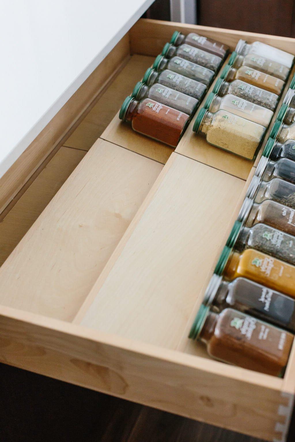 Ein Detail der Gewürzschublade mit gestuften Holzeinsätzen, die Simply Organic Gewürzgläser perfekt in alphabetischer Reihenfolge präsentieren, was die Effizienz in der Küche maximiert. #Gewürzschublade #OrdnungInDerKüche #DIYKüchenideen