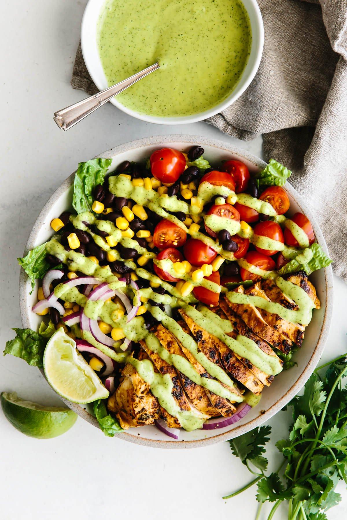 Die 20+ besten Hähnchenbrust-Rezepte 4 Südwestlicher Hähnchensalat in einer weißen Schüssel neben einer kleinen Schüssel Avocadodressing.