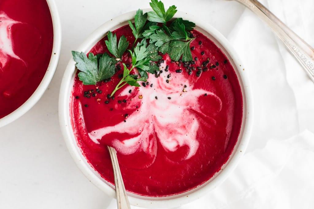 Rote Bete Suppe in einer Schüssel, garniert mit Kokoscreme und Petersilie.