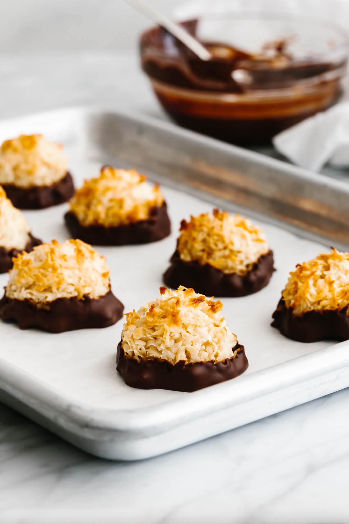 25+ Einzigartige Erntedankfest-Desserts 5 Kokosmakronen auf einem Backblech neben einer Schale Schokolade.