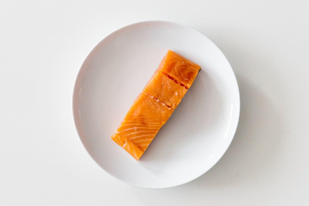 Teller mit Lachs auf einem weißen Tisch.