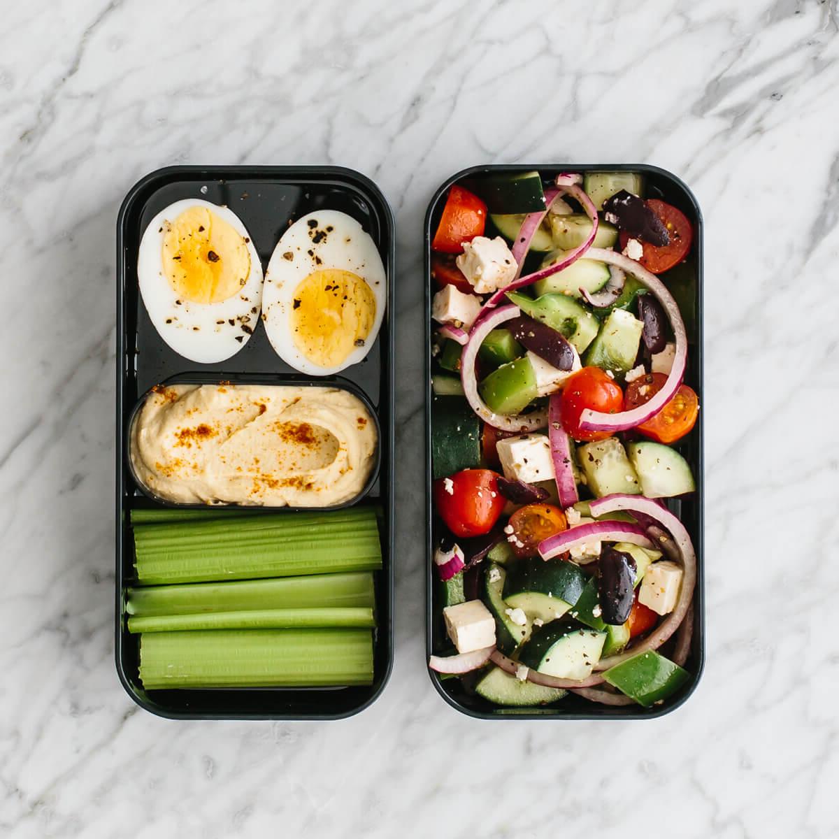 Diese gesunden Bento Lunchbox-Ideen sind perfekt für Arbeit oder Schule! Bento Box gefüllt mit griechischem Salat, hart gekochtem Ei, Sellerie und Hummus.