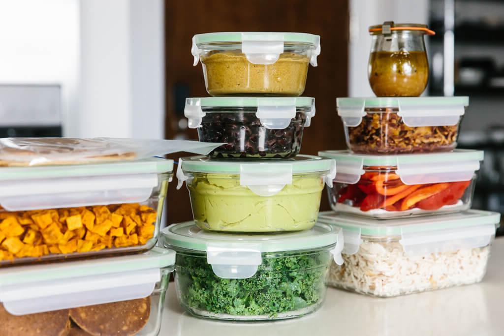 Einzelne Meal-Prep-Zutaten und fertige Gerichte sind in gestapelten Behältern organisiert, was die Effizienz und Ordnung beim vorbereiteten Kochen zeigt.