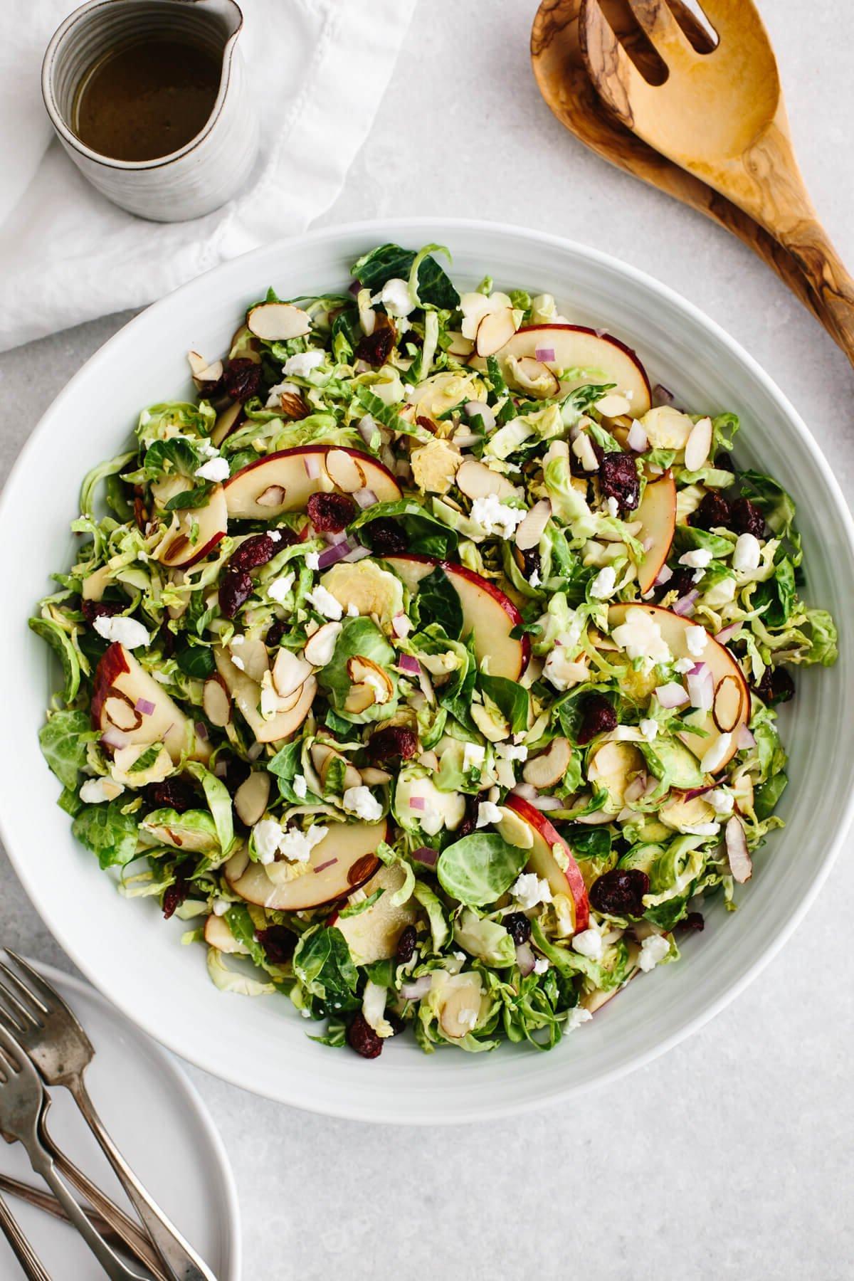 Dieses Thanksgiving-Menü bietet herbstliche Aromen, klassische Gerichte mit modernem Dreh und natürlich den ultimativen gebratenen Truthahn, den die ganze Familie lieben wird! Salat aus gehobeltem Rosenkohl in einer weißen Schüssel.