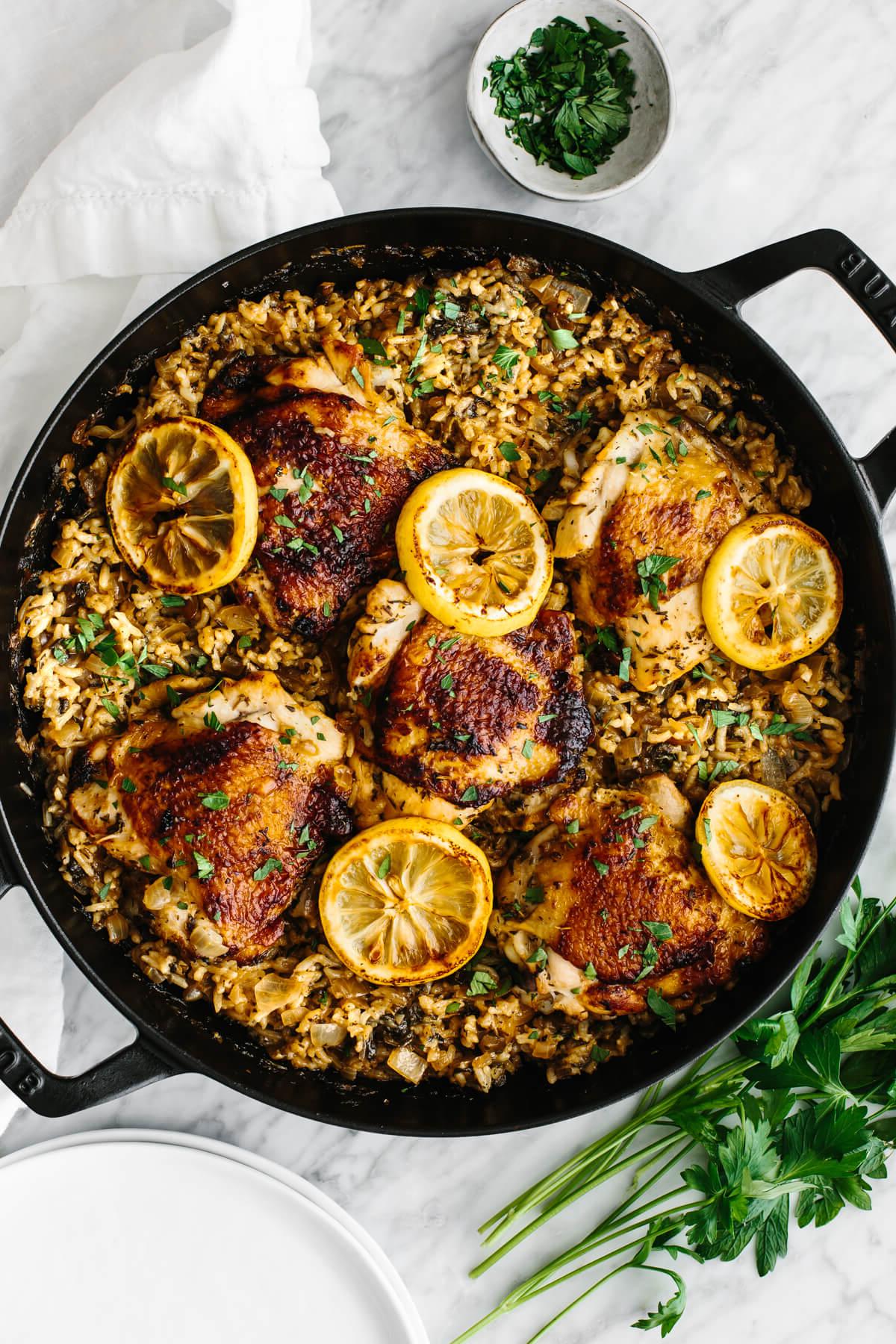 10+ Beste Hähnchenschenkel-Rezepte 6 Hähnchen und Reis in einer Pfanne, garniert mit Zitronenscheiben und Petersilie.