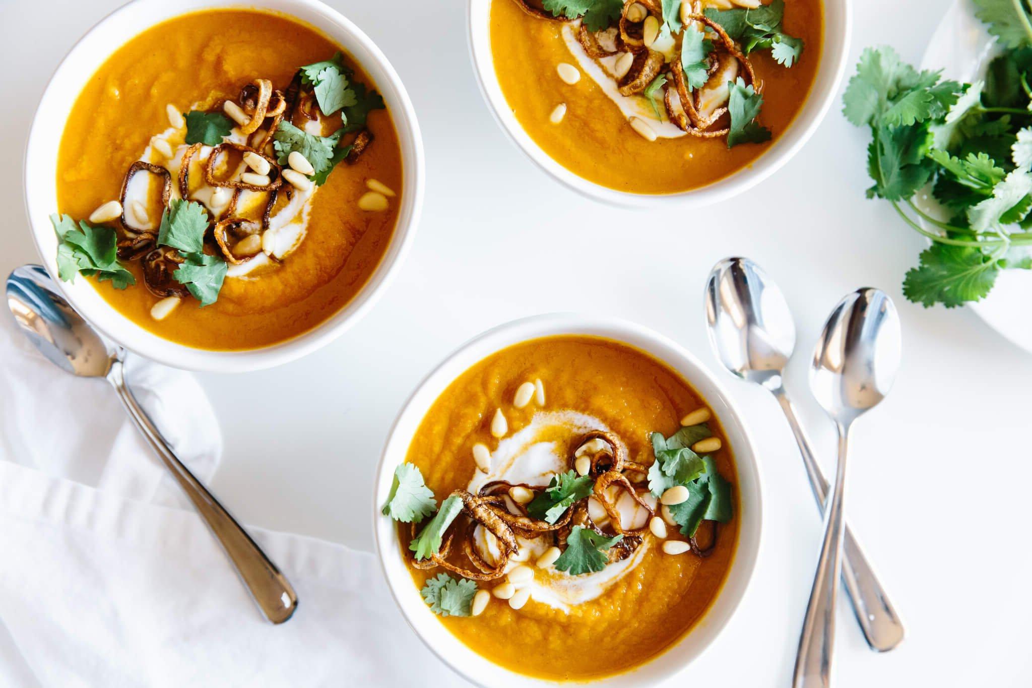 Mehrere Schüsseln Karotten-Ingwer-Suppe auf einem Tisch.