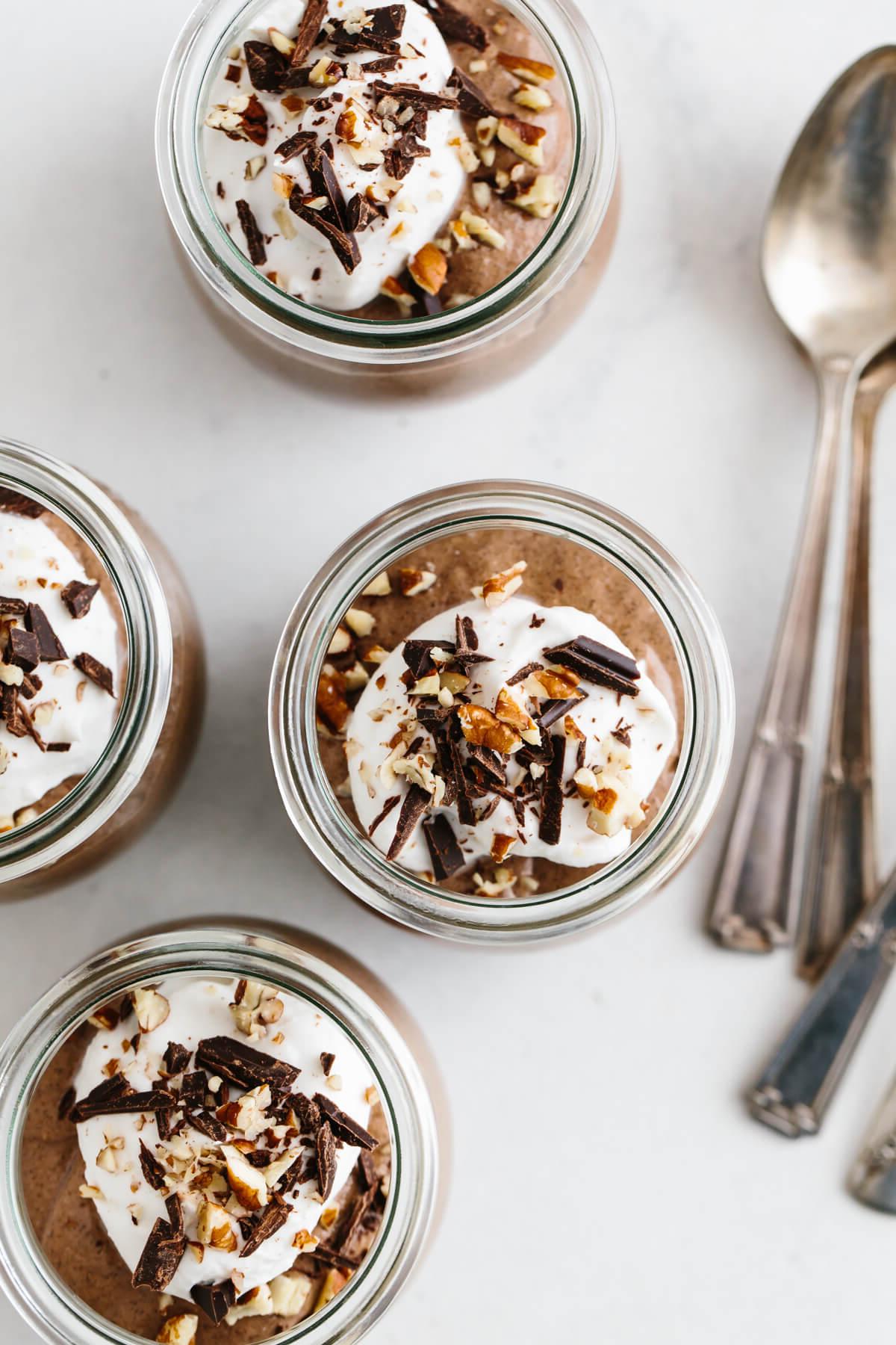 25+ Einzigartige Erntedankfest-Desserts 6 Vier Portionen Schokoladen-Chia-Mousse, garniert mit Kokos-Schlagsahne, Nüssen und Schokolade.