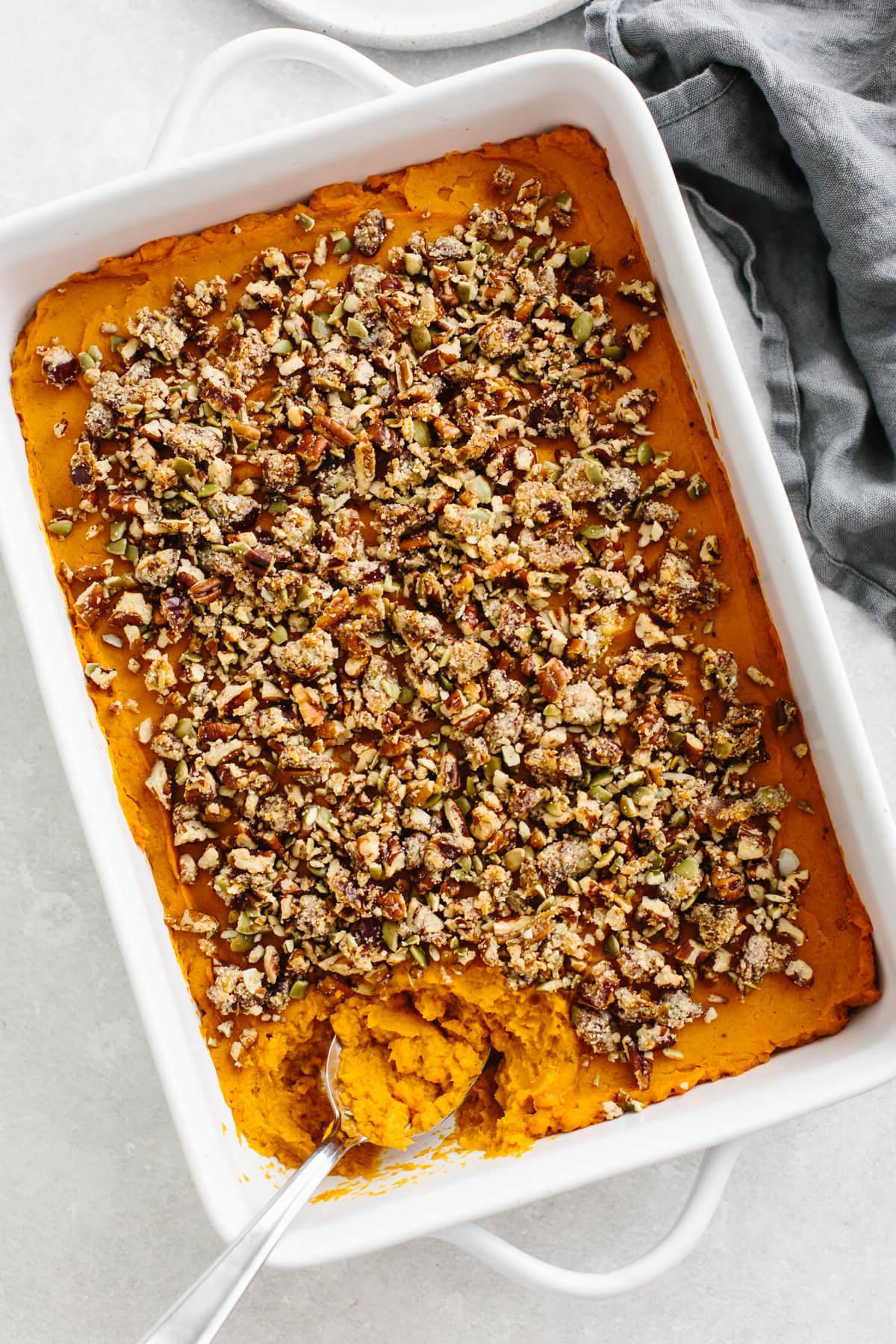 Über 15 Süßkartoffel-Rezepte zum Verlieben 6 Süßkartoffelpüree mit Pekannuss-Crumble in einer weißen Auflaufform.