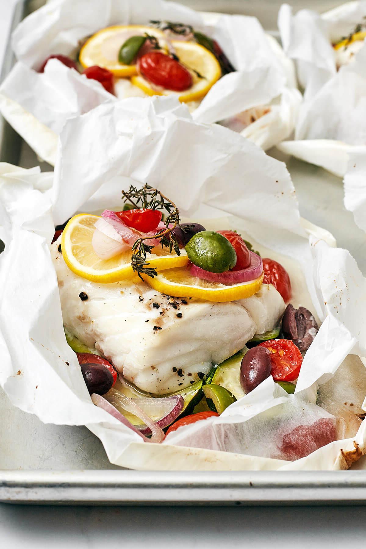 Die 60+ besten Mittelmeer-Diät-Rezepte 54 Mediterraner Kabeljau en Papillote auf einem Backblech