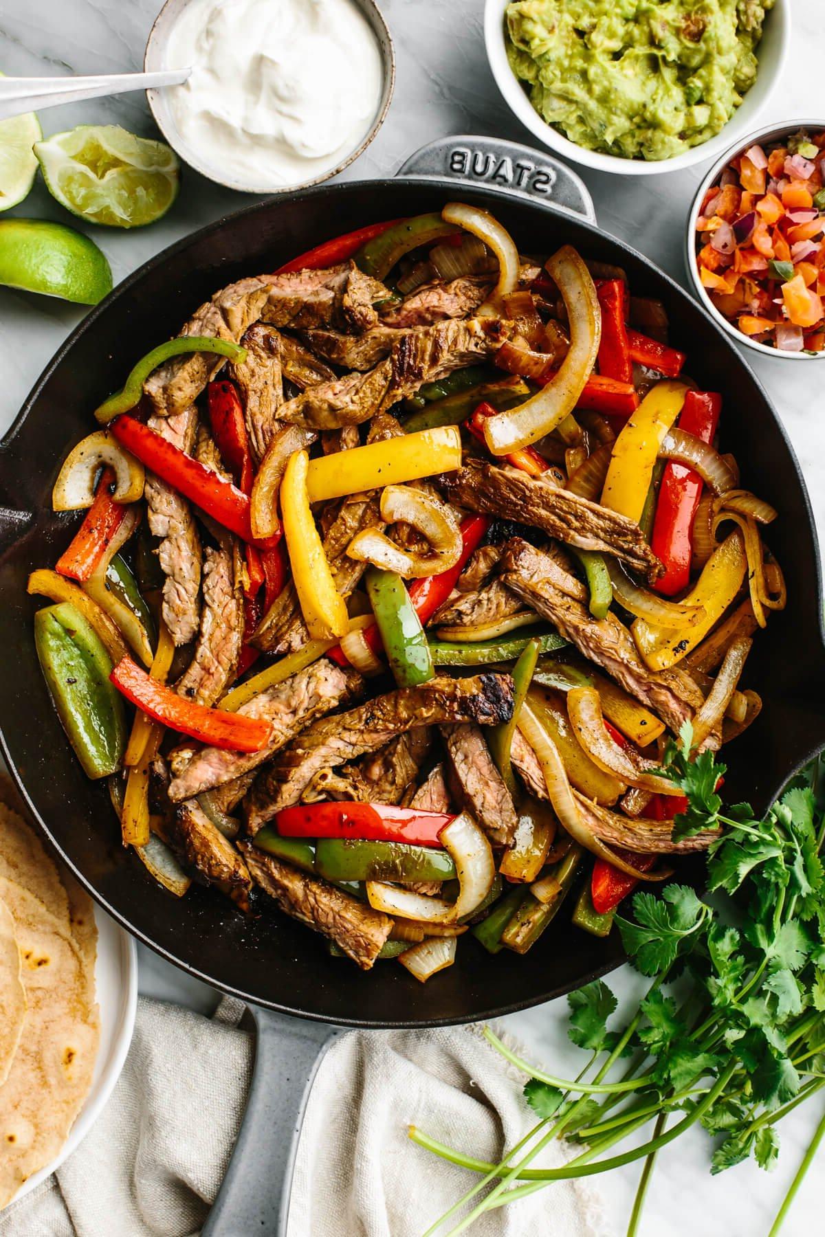 15+ einfache Grillrezepte für den Sommer 7 Steak Fajitas in einer Pfanne mit Beilagen an der Seite