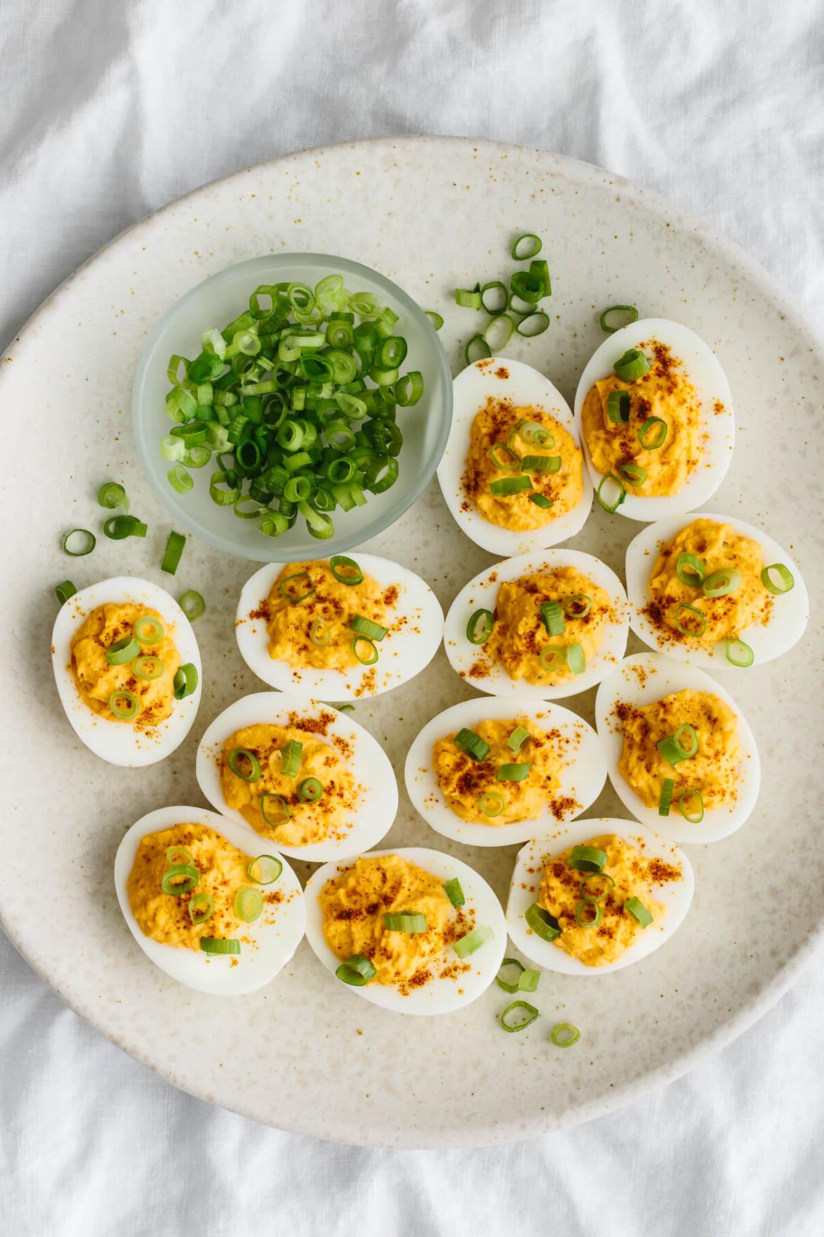 Über 40 Osterrezepte: Frisch, klassisch und einfach 7 Scharfe gefüllte Eier auf einem weißen Teller mit Frühlingszwiebeln.
