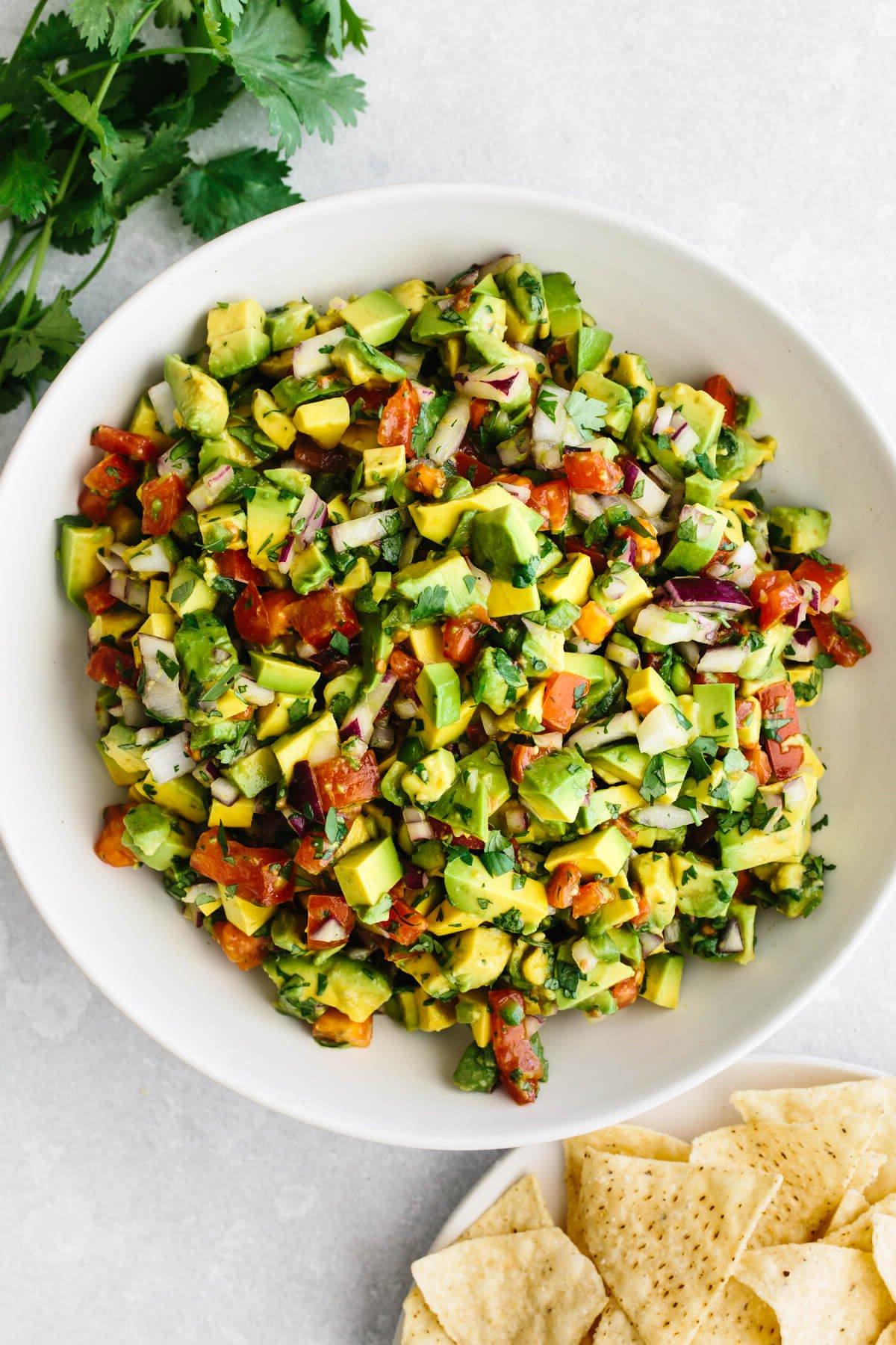 30+ Mexikanische Rezepte – Perfekt für den Cinco de Mayo 7 Eine große Schüssel Avocado-Salsa neben einem Teller Chips.