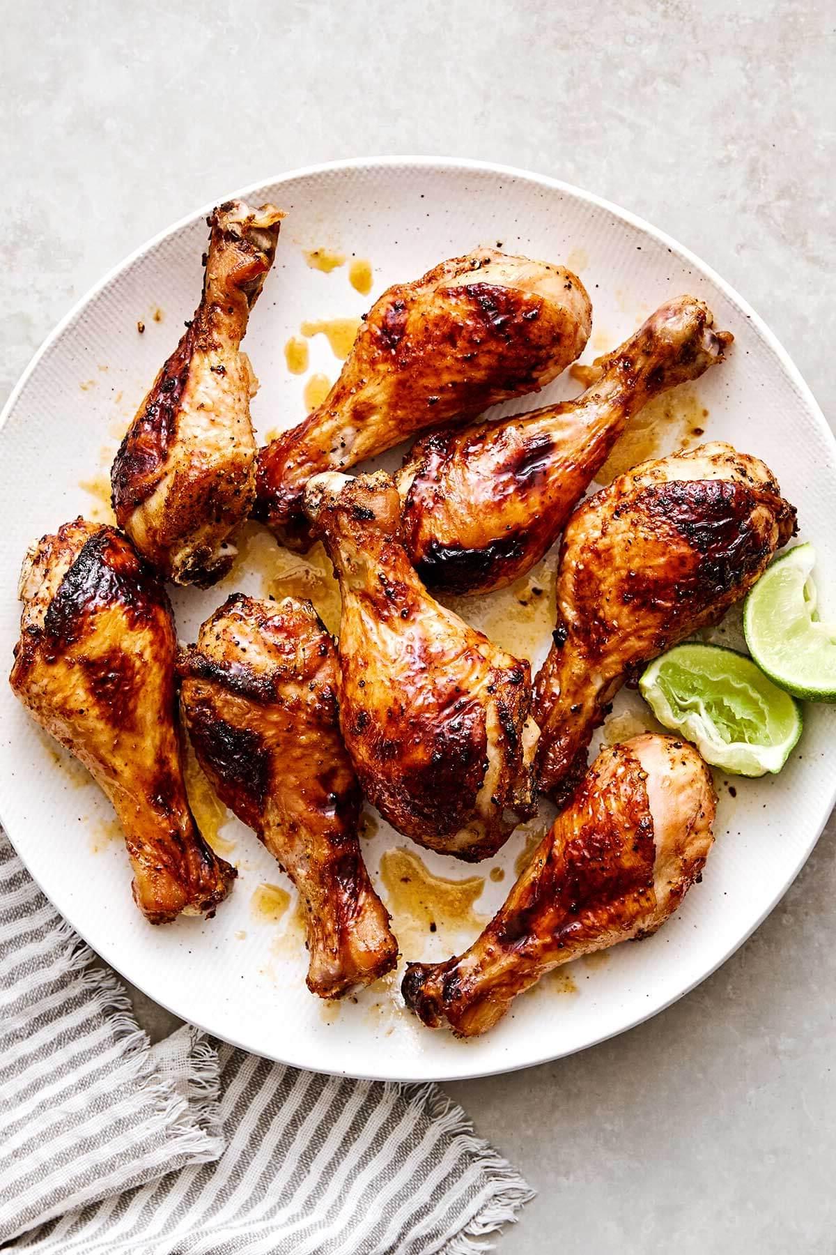 Über 30 festliche Rezepte zum 4. Juli 7 Scharfe Honig-Hähnchenkeulen mit Limetten auf einem Teller.