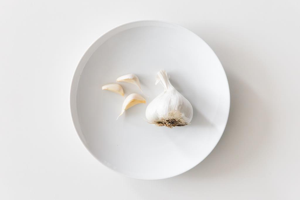 Teller mit Knoblauch auf einem weißen Tisch.