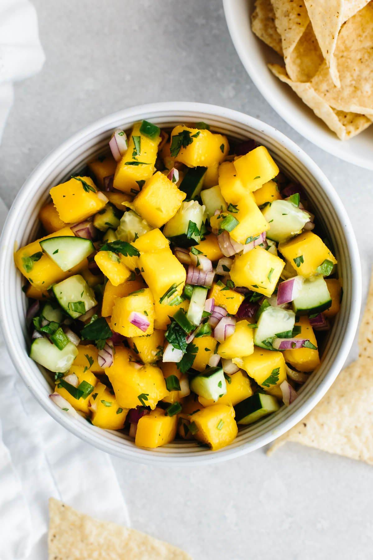 30+ Mexikanische Rezepte – Perfekt für den Cinco de Mayo 8 Mango-Salsa in einer Schüssel neben Chips.