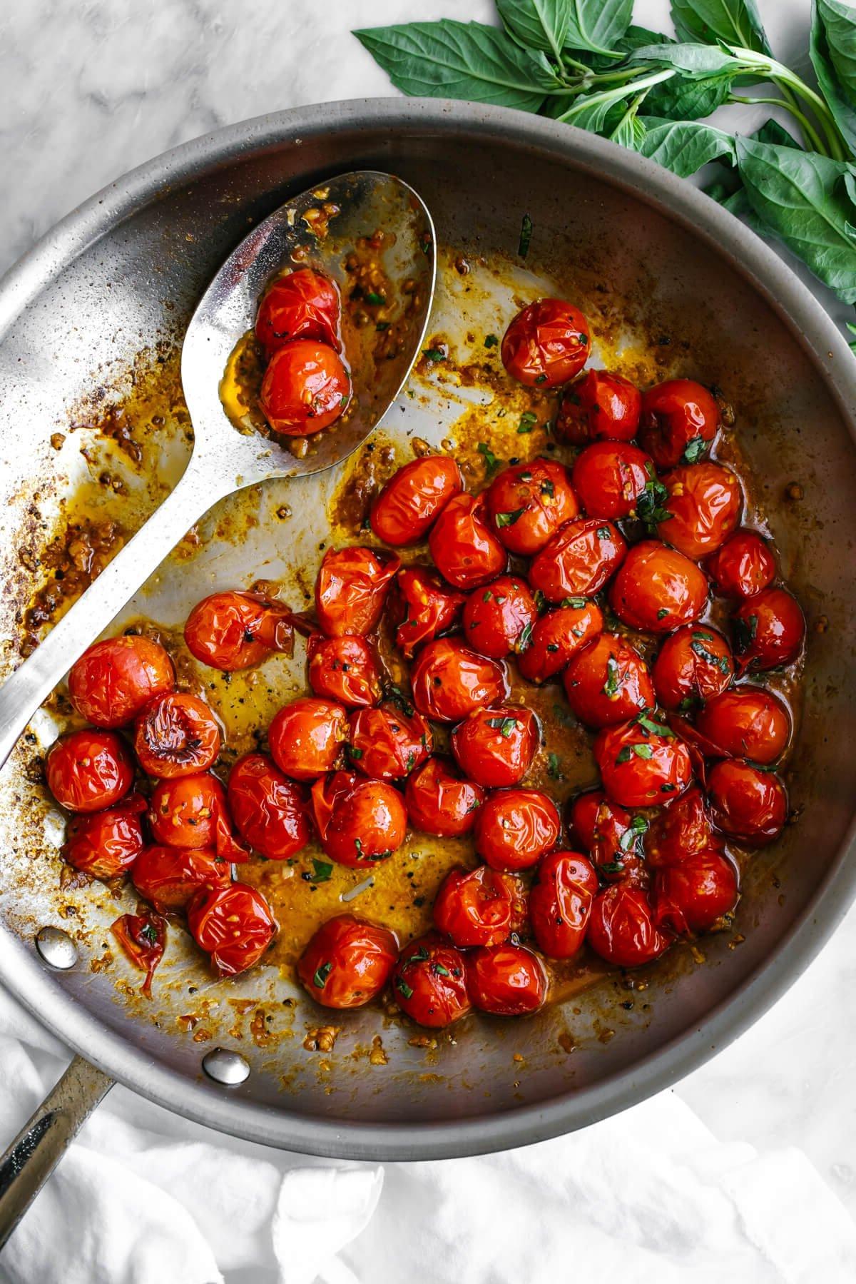 Über 50 einfache Whole30 Abendessen-Rezepte 79 Blistertomaten in einer Pfanne mit einem großen Servierlöffel.