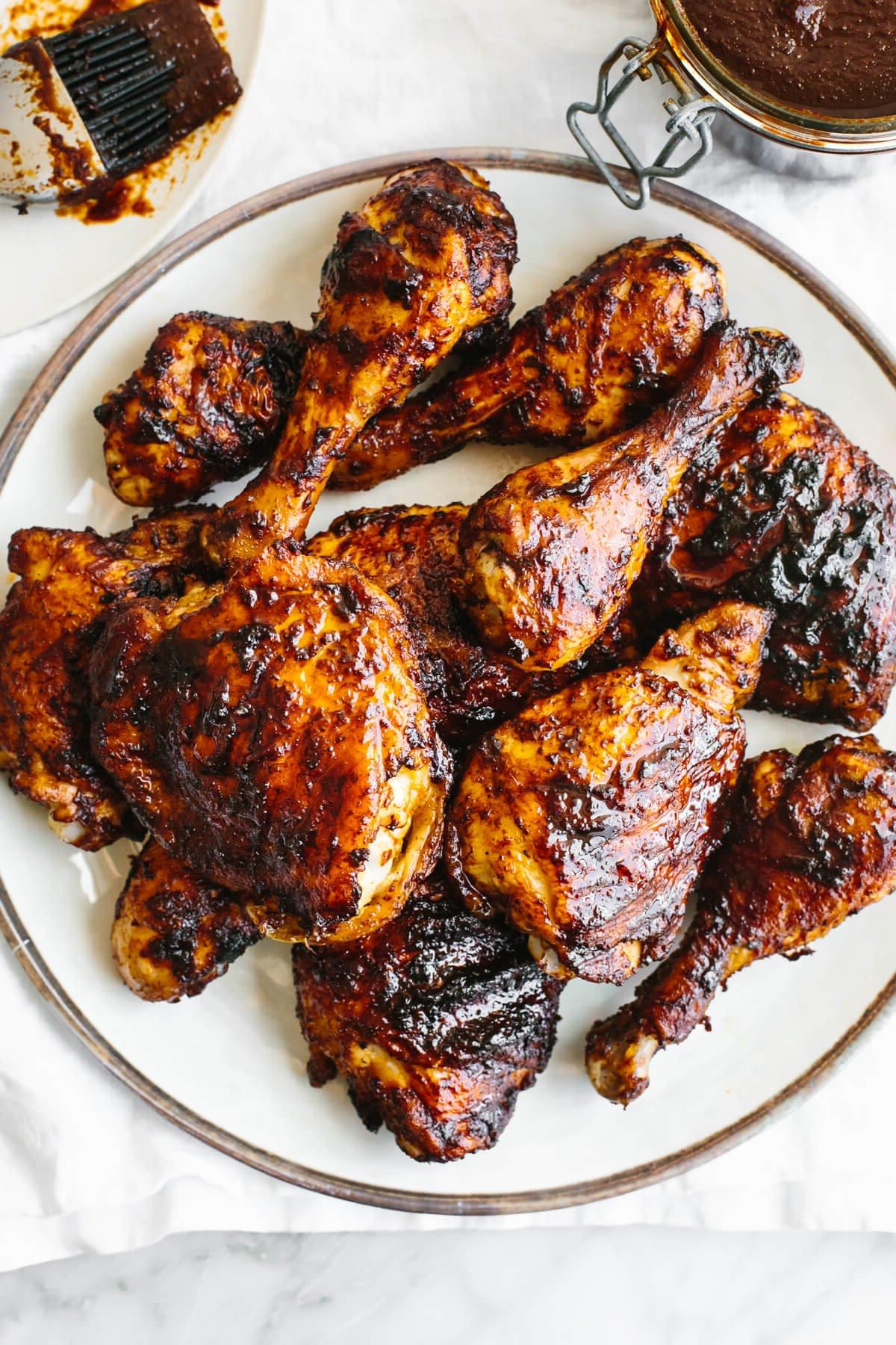 10+ Beste Hähnchenschenkel-Rezepte 9 Ein Teller mit BBQ-Hähnchen auf einem weißen Teller und einer Serviette.