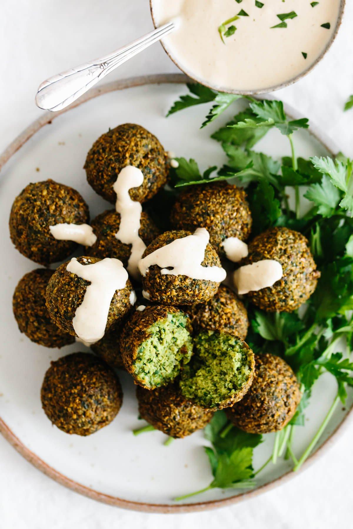 Ein Teller Falafel, beträufelt mit Tahini-Sauce.