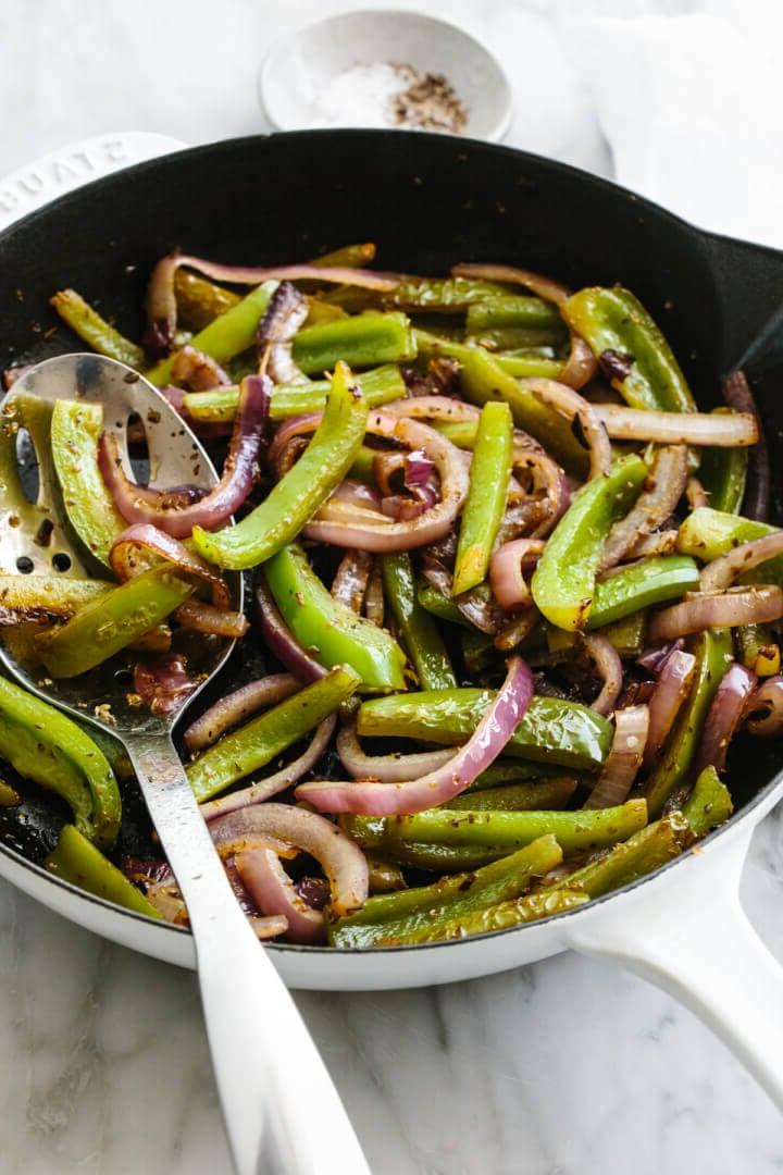 Fajita-Gemüse in einer Pfanne mit einem Schaumlöffel.