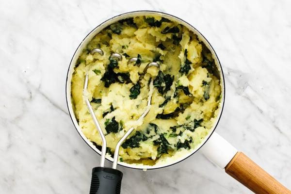 Colcannon in einem Topf stampfen.