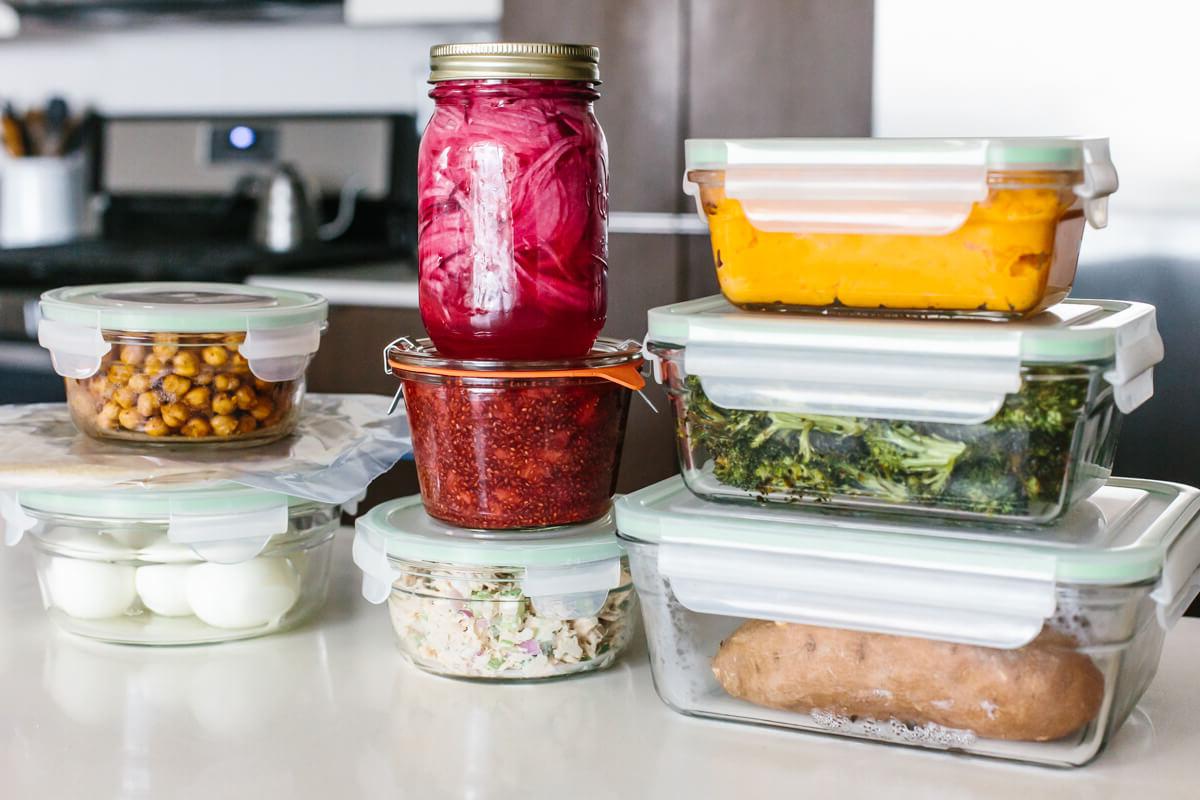 Dieses preiswerte Meal Prep zeigt, dass gesunde Ernährung nicht teuer sein muss. Verwandeln Sie 11 vorbereitete Zutaten in 7 Mahlzeiten, die jeweils 3€ oder weniger kosten! Gestapelte Behälter auf einem Tisch für ein gesundes, budgetfreundliches Meal Prep