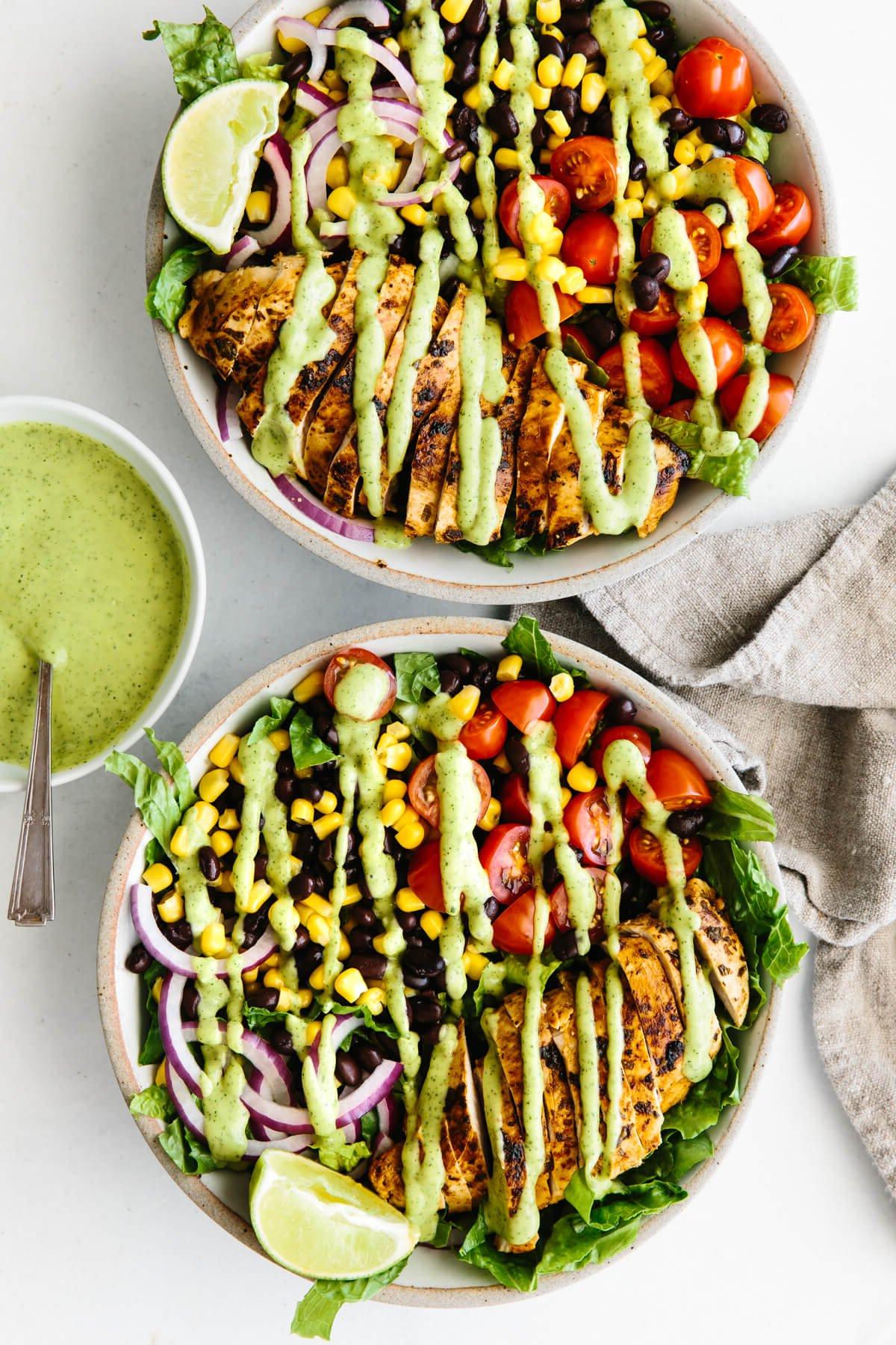 Über 40 einfache und gesunde Salatrezepte 4 Zwei Southwest-Hähnchensalate mit Avocado-Dressing beträufelt.