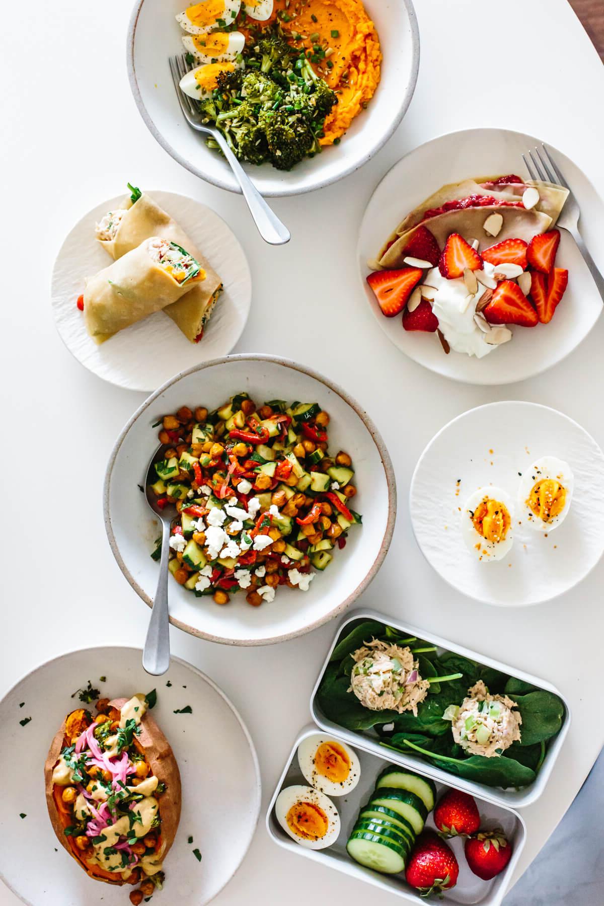 Dieses gesunde, budgetfreundliche Meal Prep verwandelt 11 vorbereitete Zutaten in 7 Mahlzeiten (Frühstück, Mittagessen und Abendessen), die 3€ oder weniger kosten! Mahlzeiten auf einem Tisch ausgelegt für eine budgetfreundliche Meal-Prep-Zubereitung