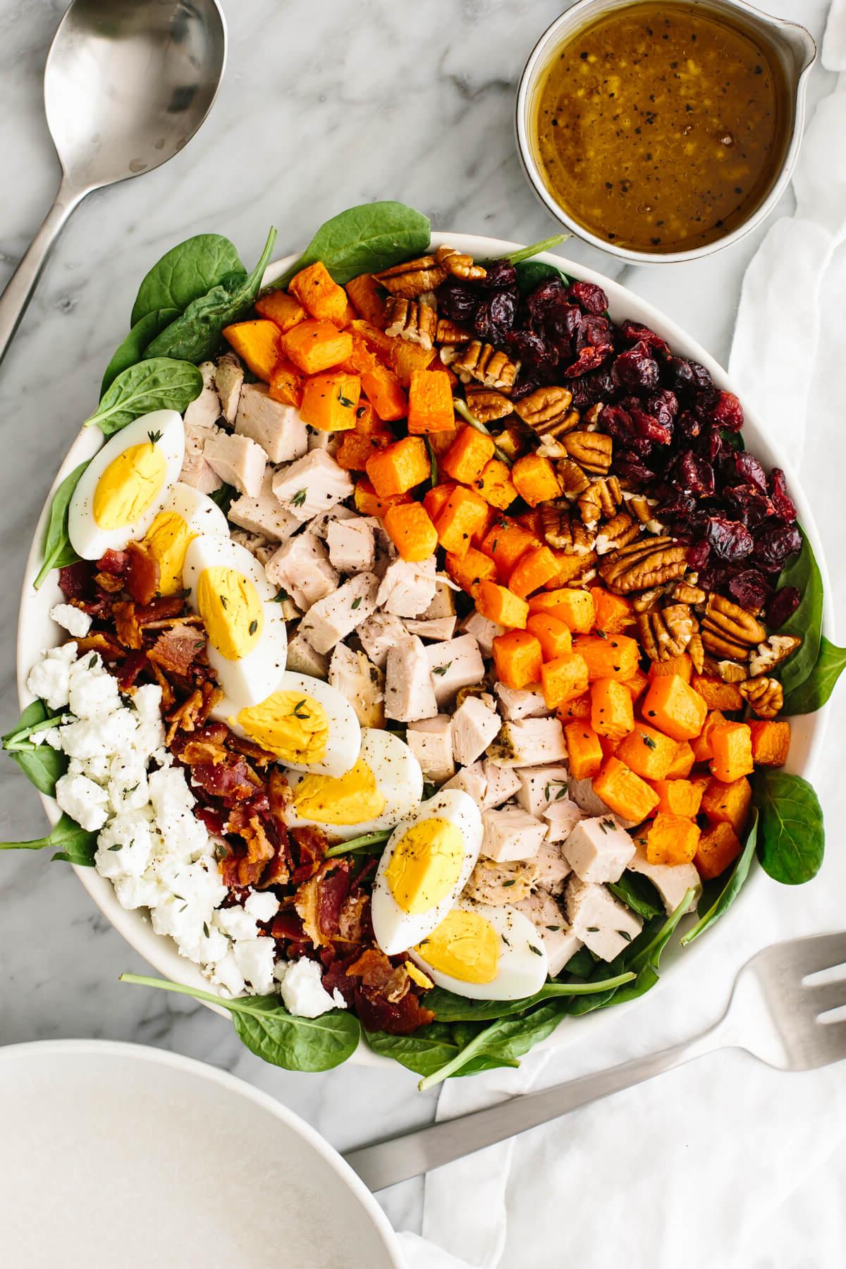 Über 40 einfache und gesunde Salatrezepte 6 Truthahn-Cobb-Salat in einer großen Schüssel auf einem Tisch neben einem Löffel.