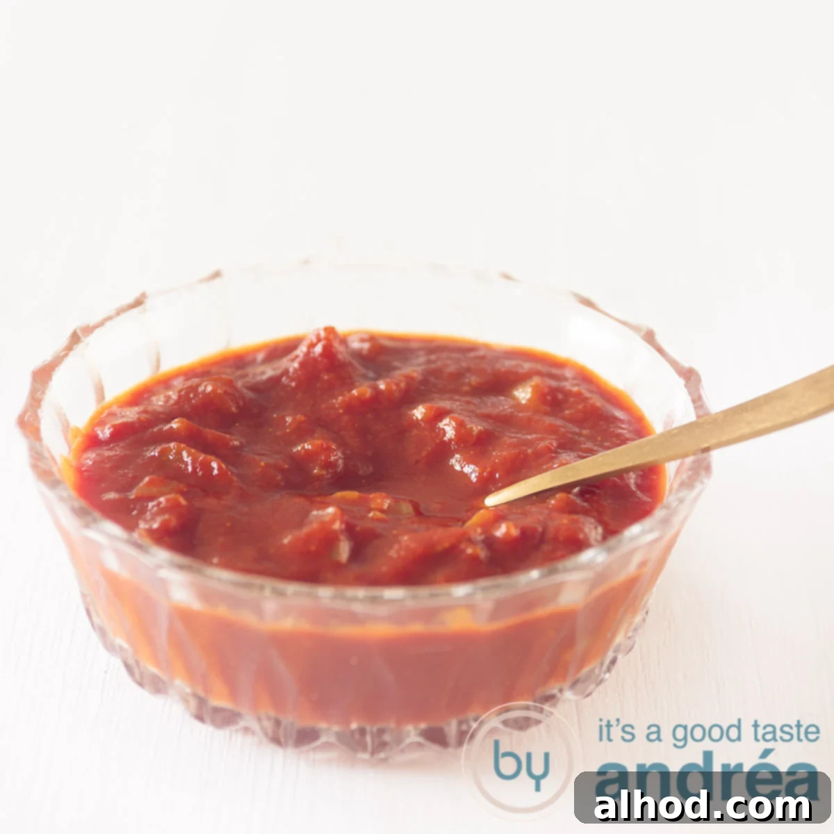 5 Homemade Sauces for the Ultimate Raclette Experience 5 A glass bowl filled with homemade curry sauce on a white background. A golden spoon put in the sauce