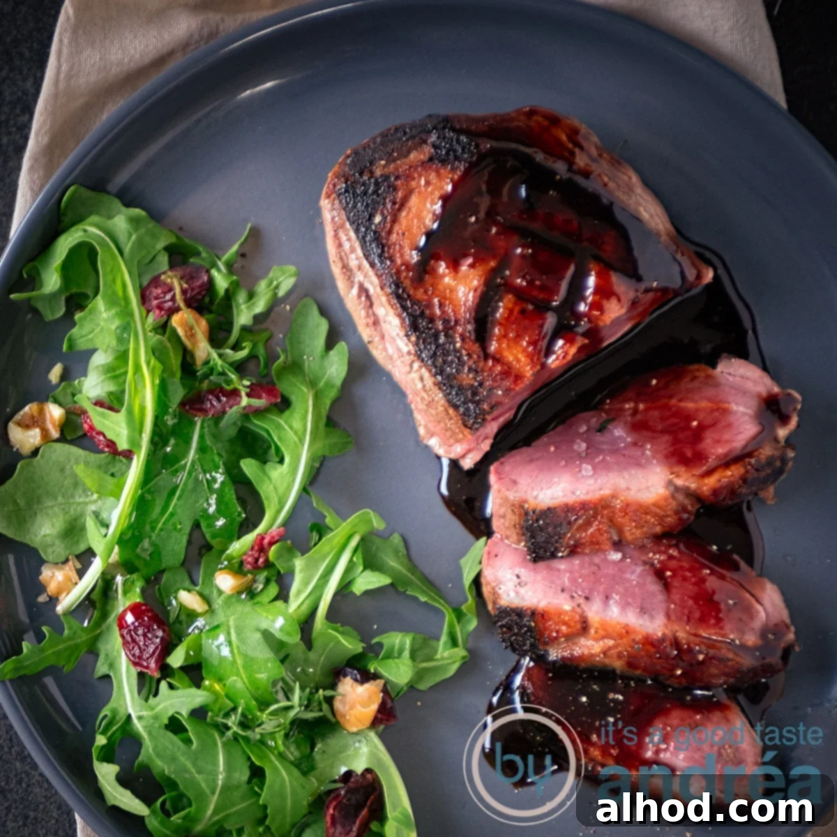10 Festive Christmas Mains & Sides 10 A square photo of a gray plate with duck breast fillet, 3 slices cut off and a balsamic sauce with honey