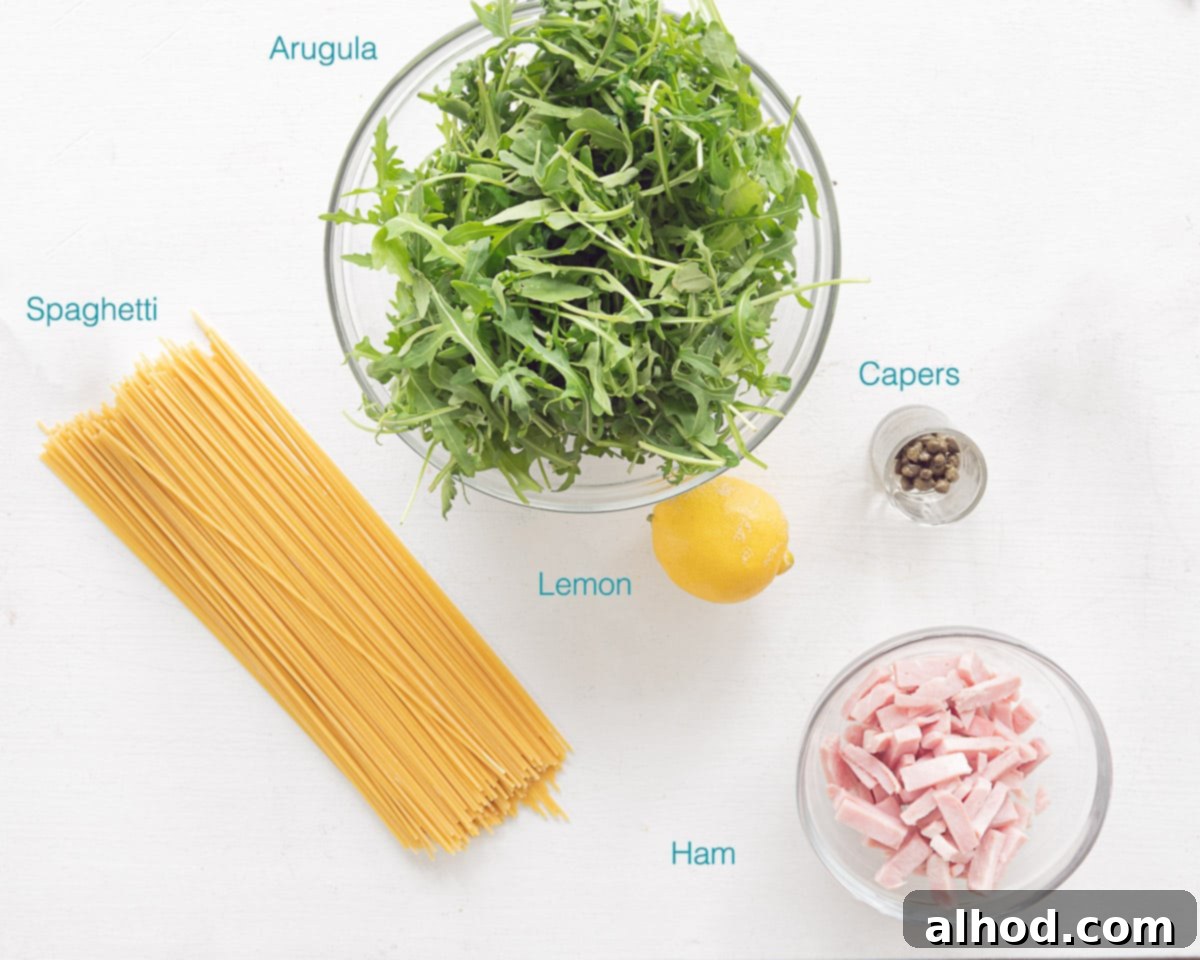Hearty Italian Ham Spaghetti 3 Individual ingredients for Italian Spaghetti with Ham laid out neatly on a white background, highlighting fresh lemon, ham cubes, arugula, capers, and spaghetti.