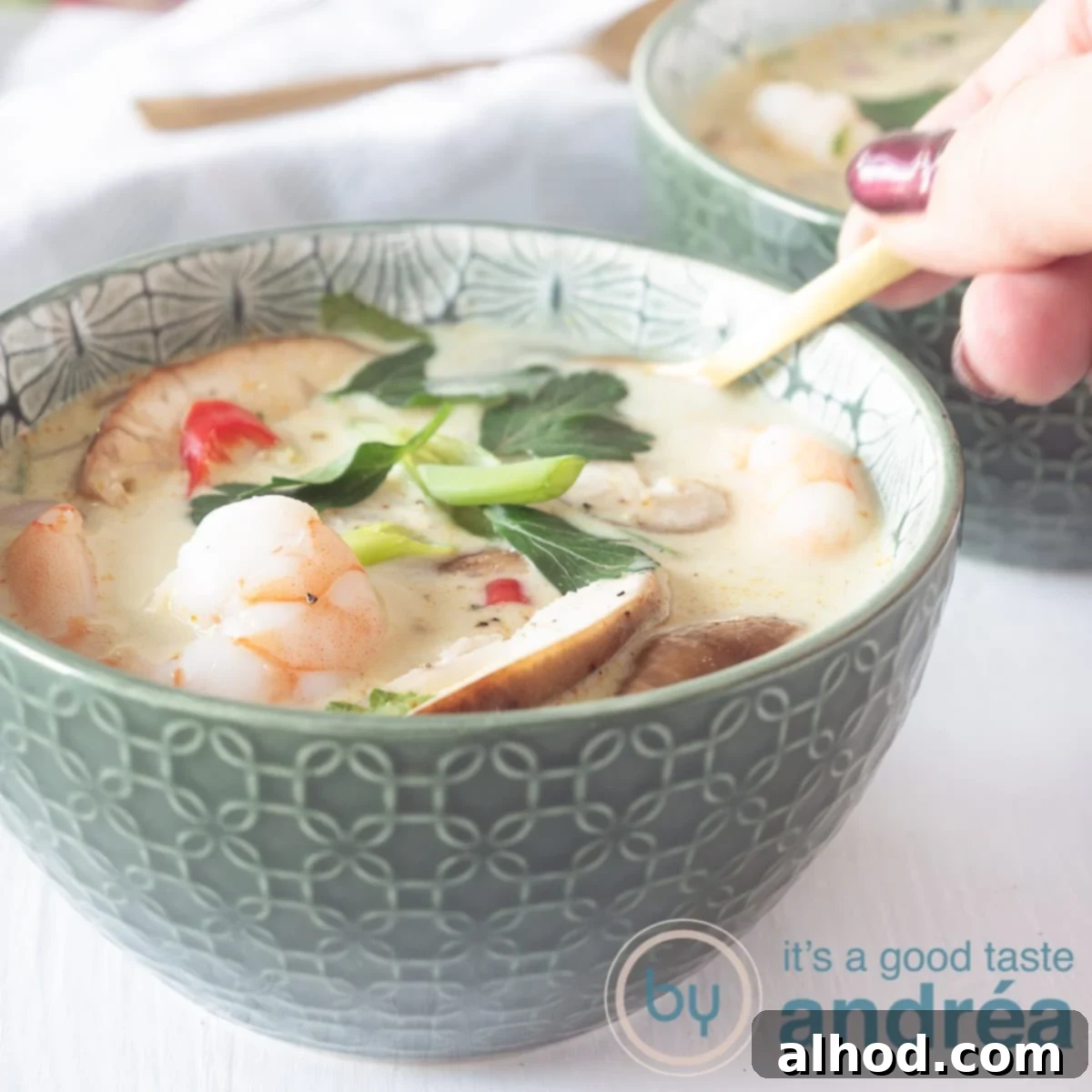 Tom Kha Goong Thai Coconut Shrimp Soup 6 A square photo with a filled bowl with Thai coconut soup with shrimp.