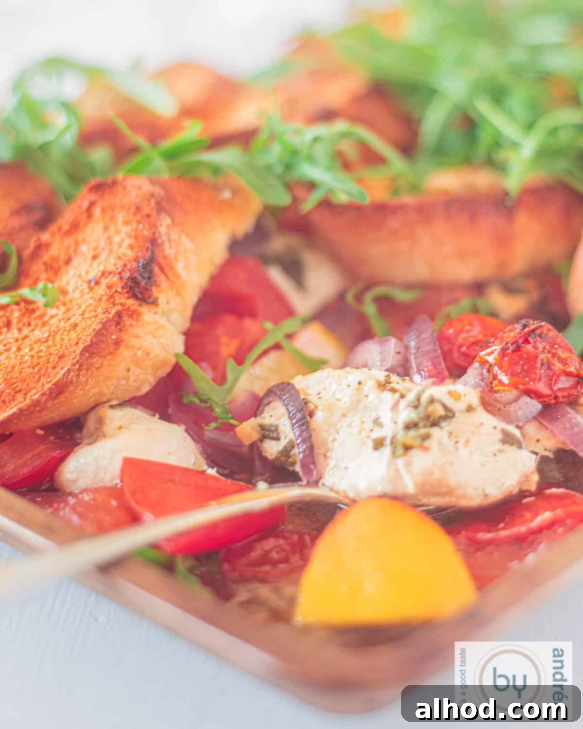 Sheet Pan Italian Herb Chicken and Veggies 2 Italian casserole with chicken, lemon, tomato and arugula on a white background