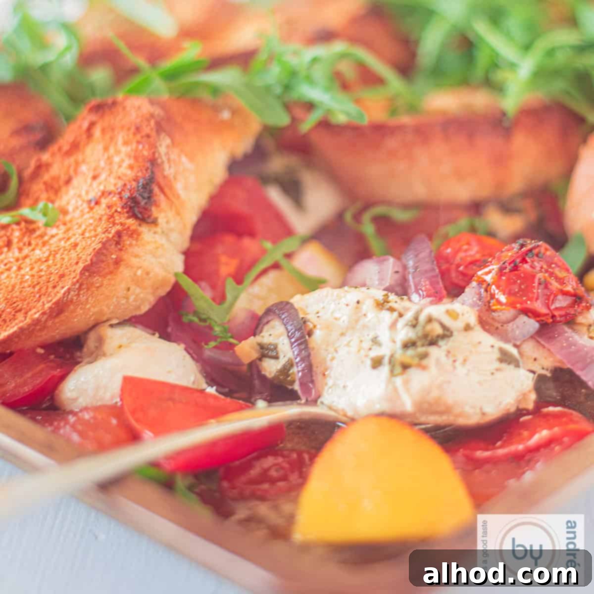 Sheet Pan Italian Herb Chicken and Veggies 4 A square photo of an Italian casserole with lemon, tomato, and arugula